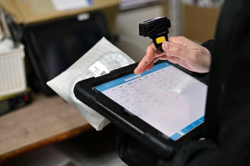 バーコードスキャナーを装着した手元でLuckPit WMSを操作しているタブレット画面